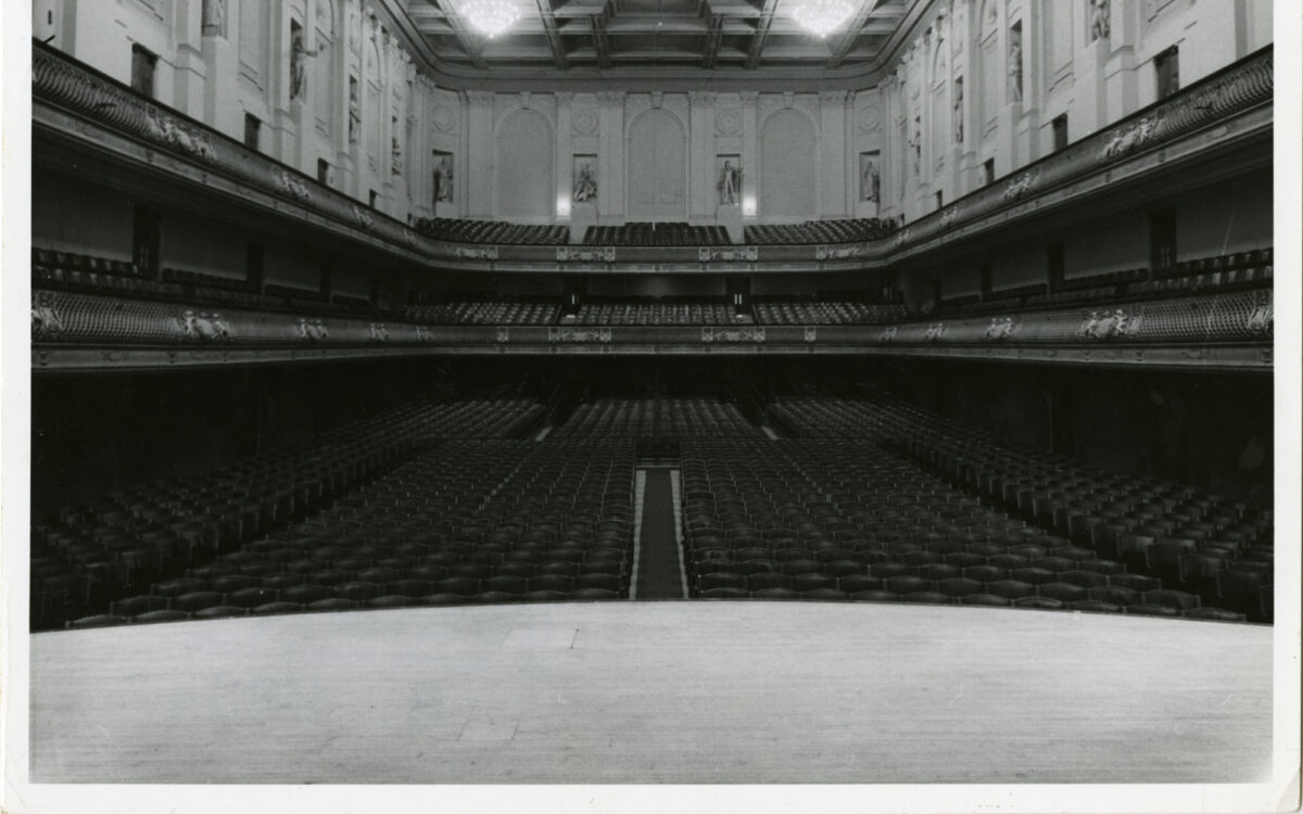 View from empty stage of the Symphony Hall auditorium with no audience, the seats slope upwards on the raked flooring