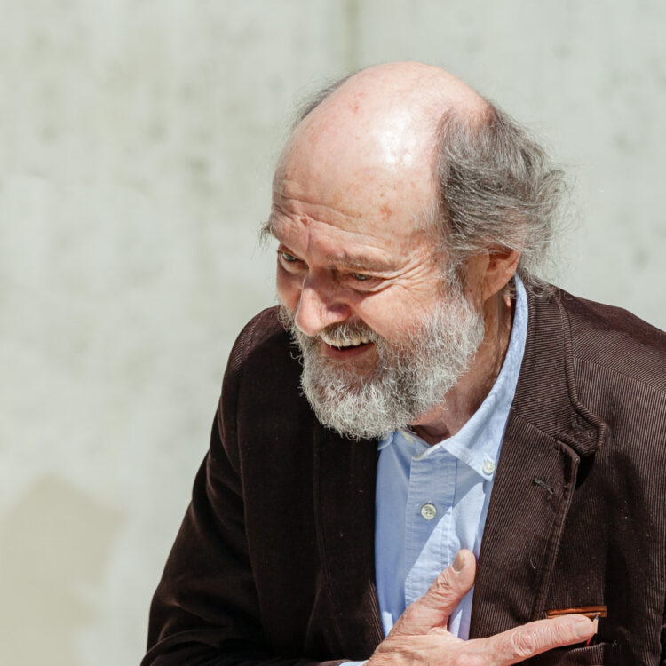 Arvo Pärt holding a paper and smiling