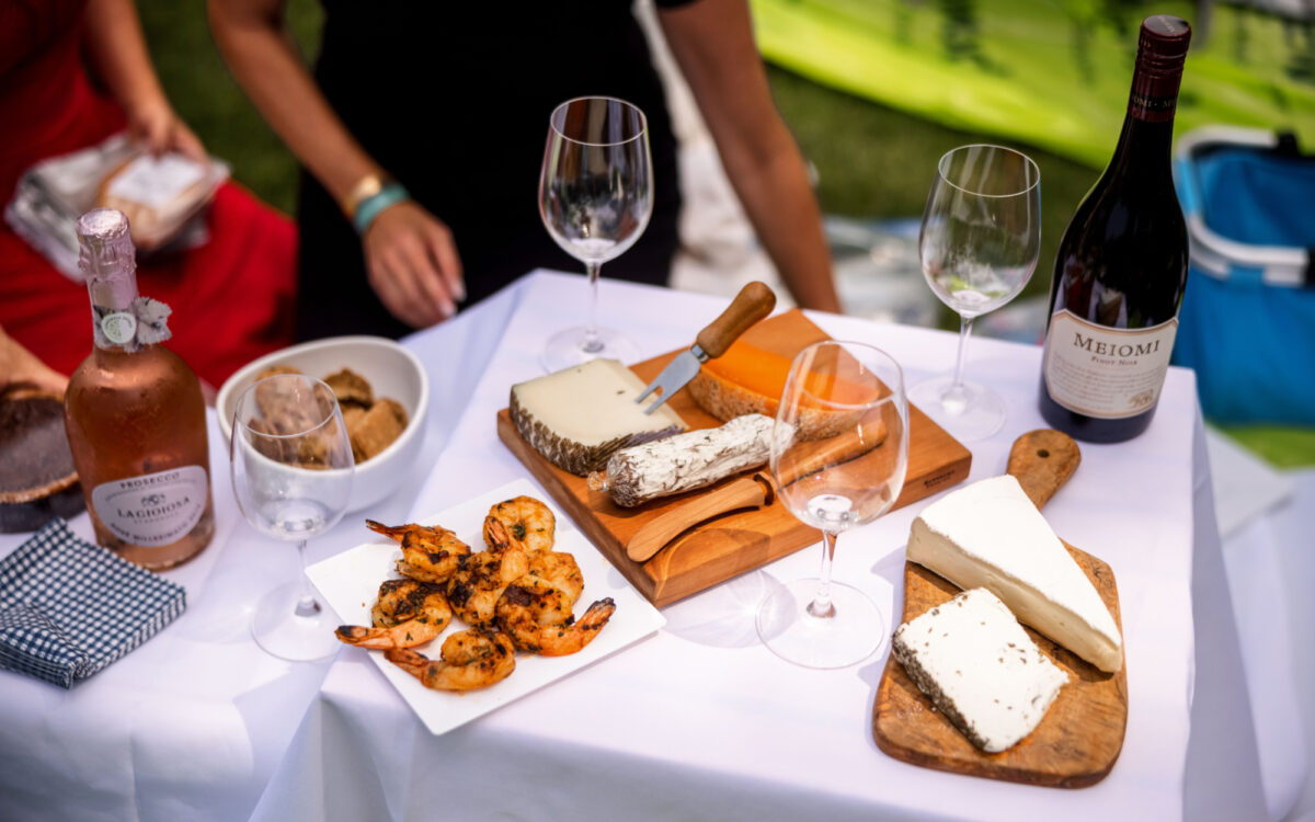 Table covered in white tablecloth with shrimp, wine, and cheese on top