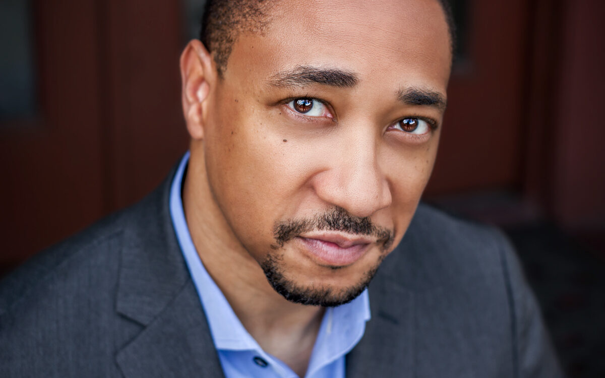 Headshot of Damon Gupton wearing a grey suit and a blue collared shirt