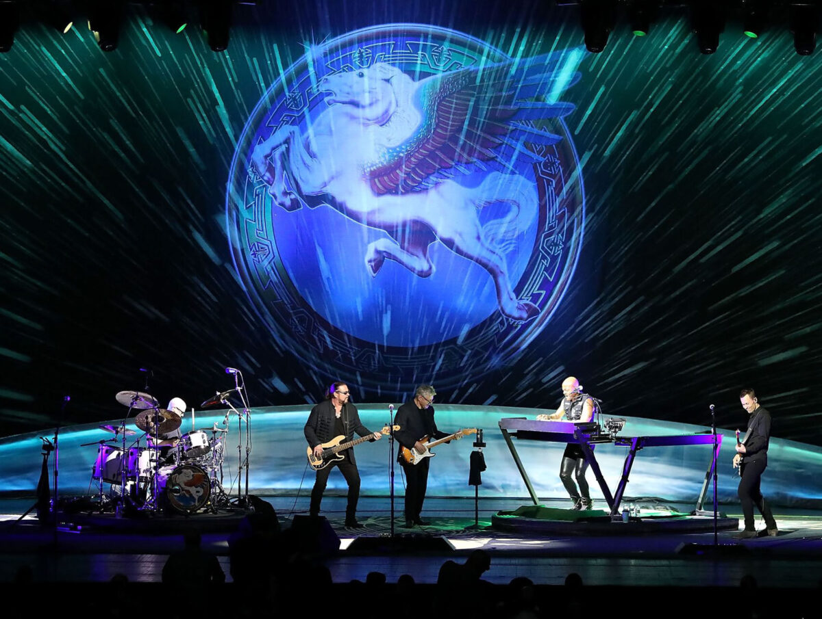 Steve Miller Band performing on stage with Pegasus logo projected behind them