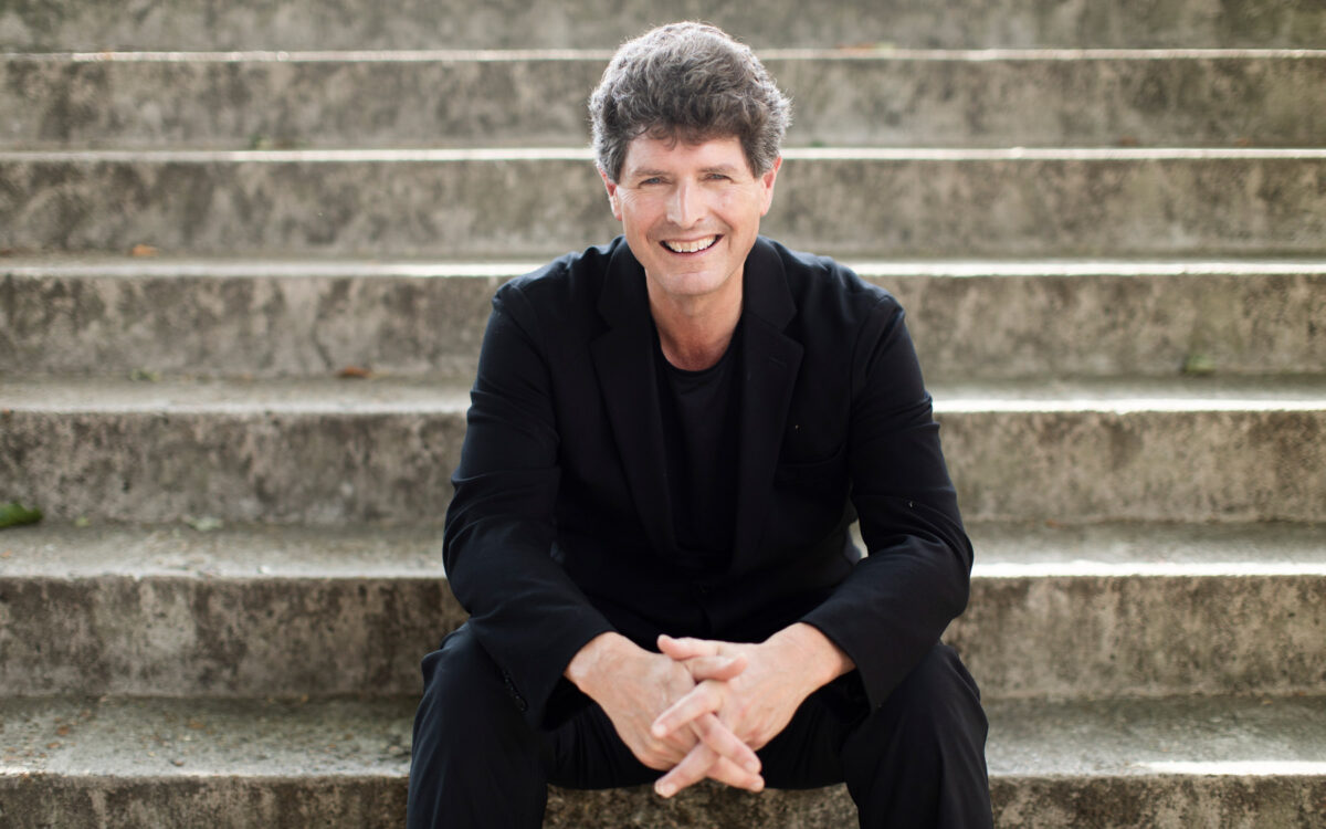 Clark Rundell sitting on stairs with a big smile