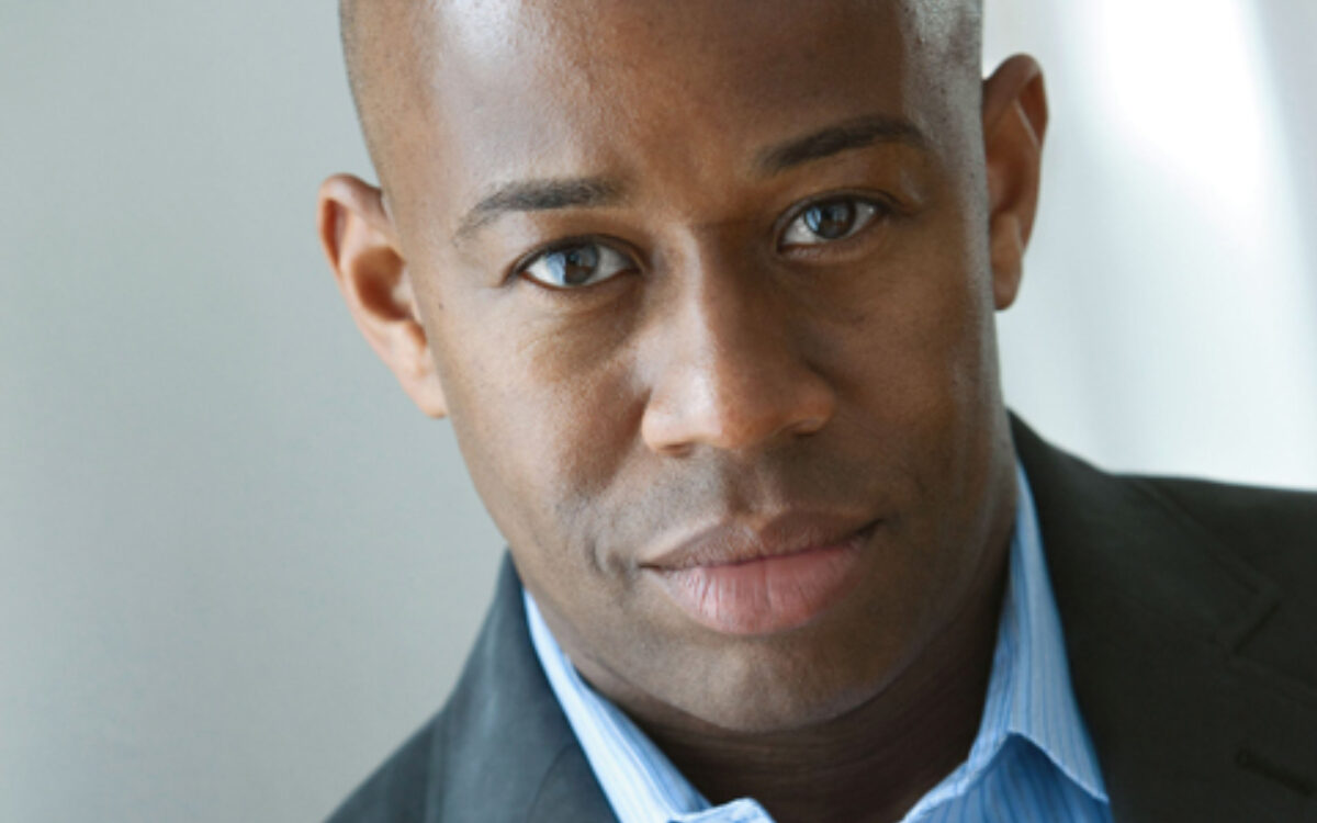 André Raphel portrait wearing a blue shirt and a dark jacket