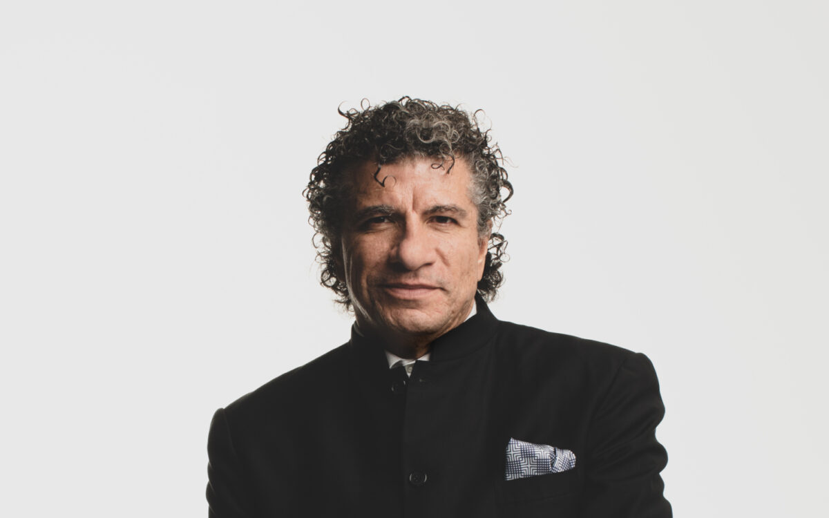 Giancarlo Guerrero sitting on a stool in front of a beige background