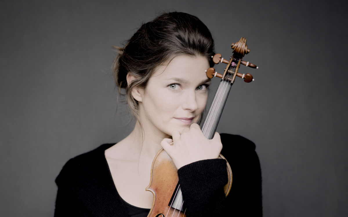 Janine Jansen holding her violin in front of a grey background