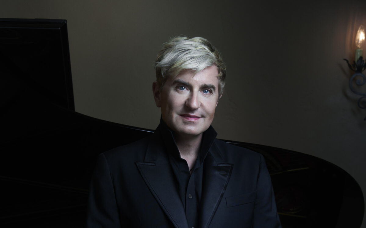 Jean-Yves Thibaudet standing in front of a piano, wearing all black