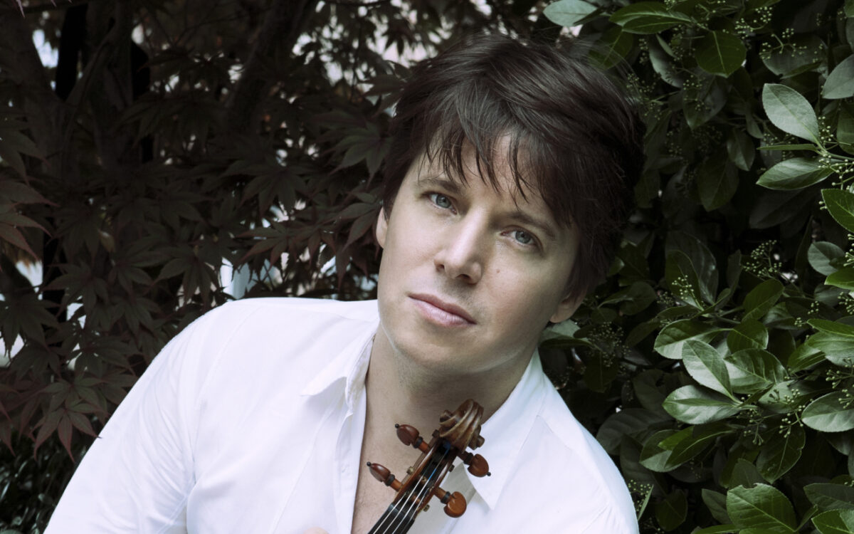 Joshua Bell holding his violin while sitting outside