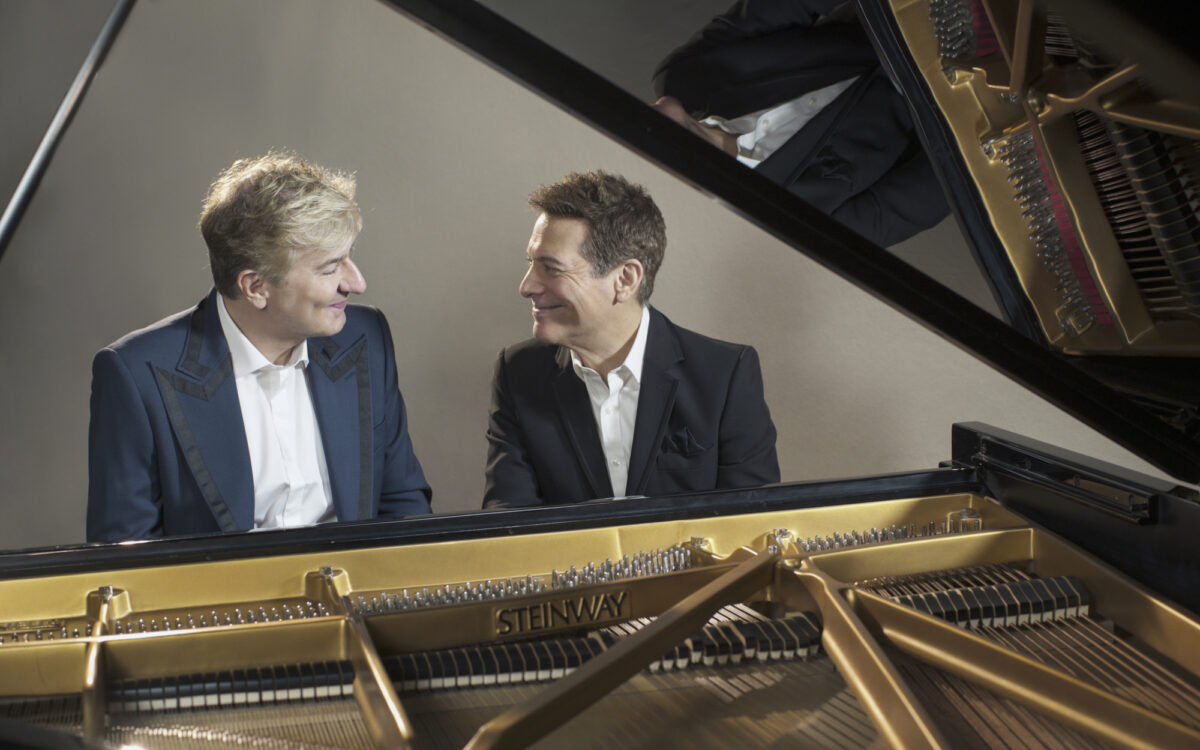 Jean-Yves Thibaudet and Michael Feinstein sitting in front of a piano, smiling at each other