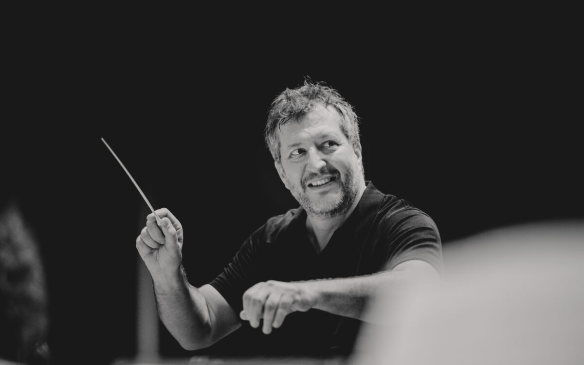 Thomas Adès with a large smile while conducting
