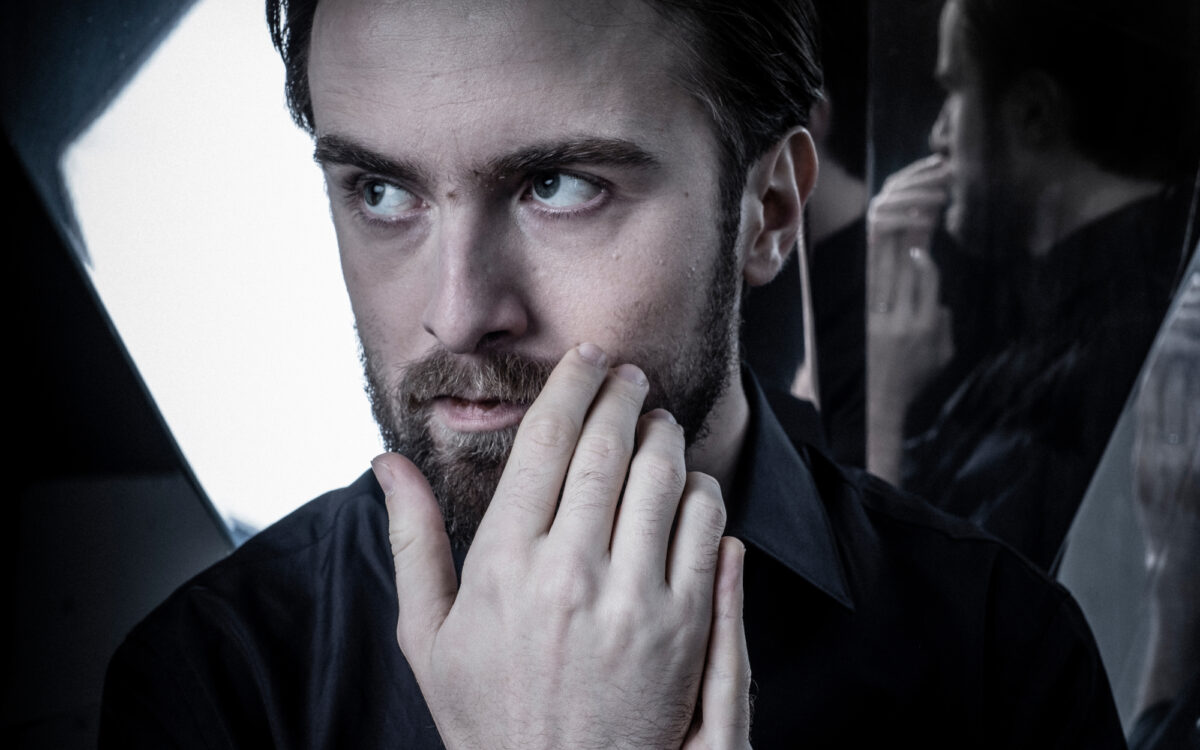 Daniil Trifonov standing in front of a mirror with his hands in front of his face