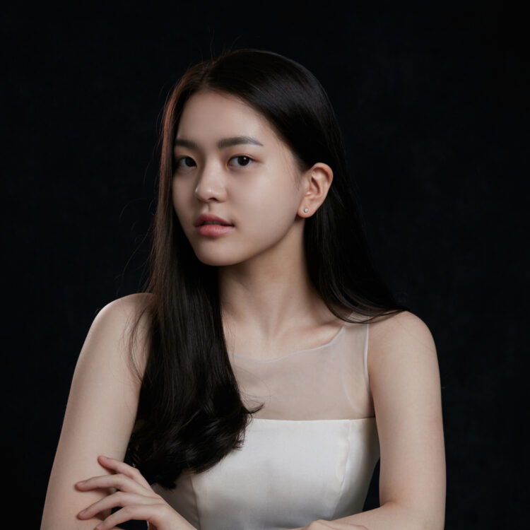 Jinyoung Kweon sitting with her arms crossed and wearing an ivory top