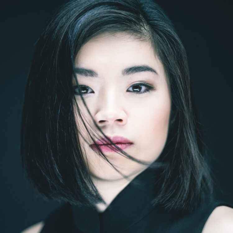 Elim Chan standing against a black background