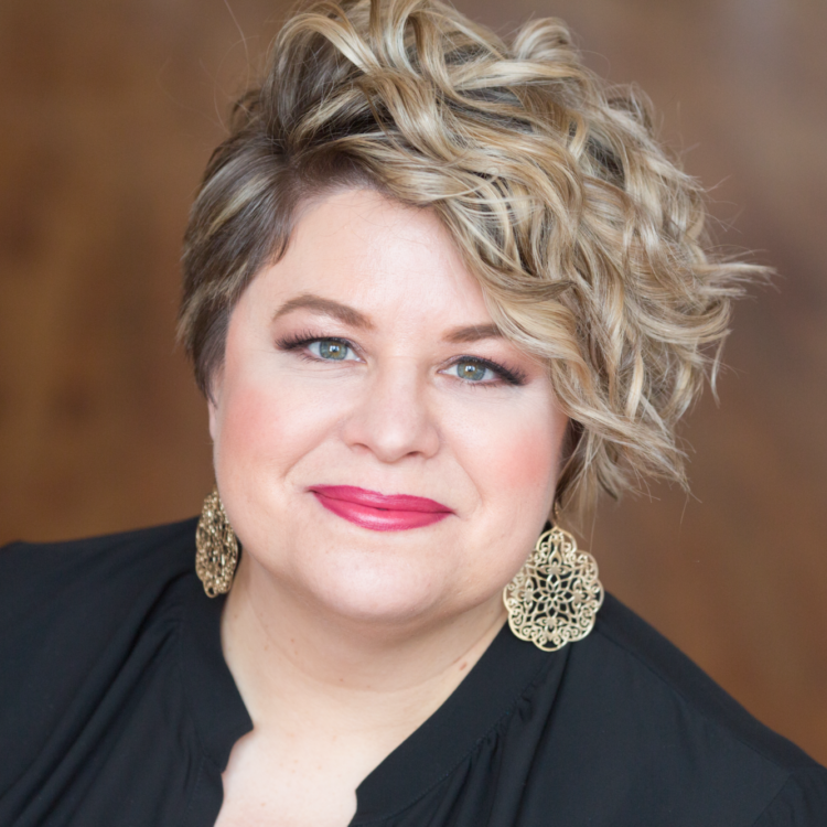 Amber Wagner headshot wearing decorative gold earrings and a black top