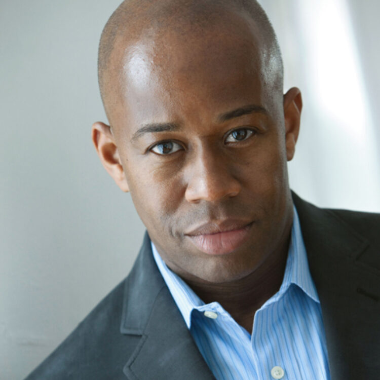 André Raphel portrait wearing a blue shirt and a dark jacket