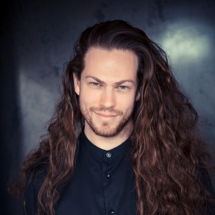 Cody Quattlebaum wearing a black shirt with his hair down and draped over his shoulders.