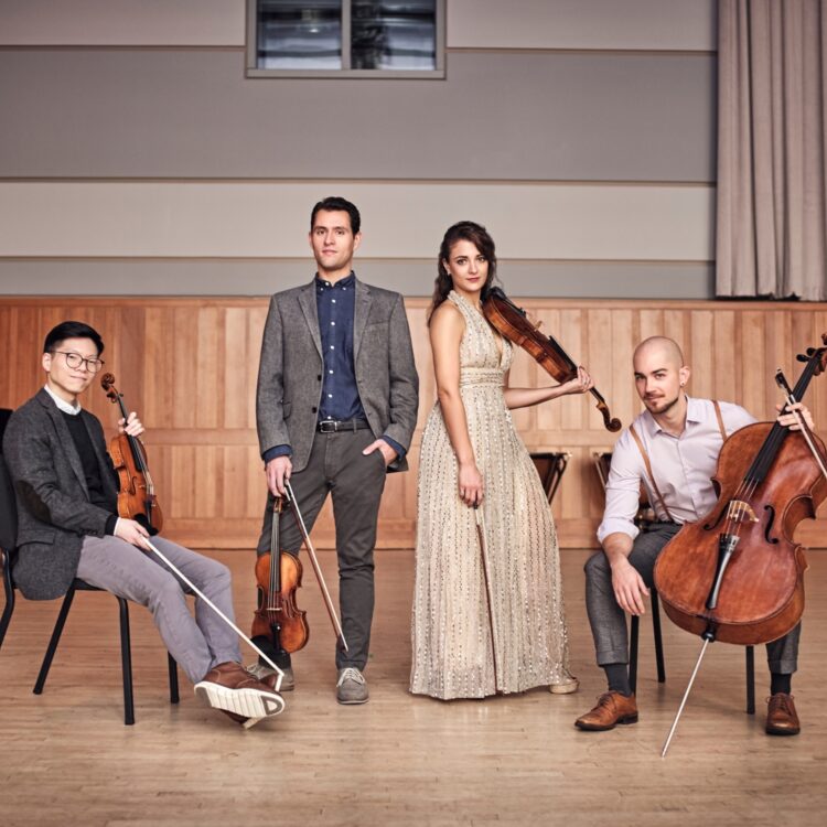 Group photo of the Dover Quartet dressed up holding their instruments