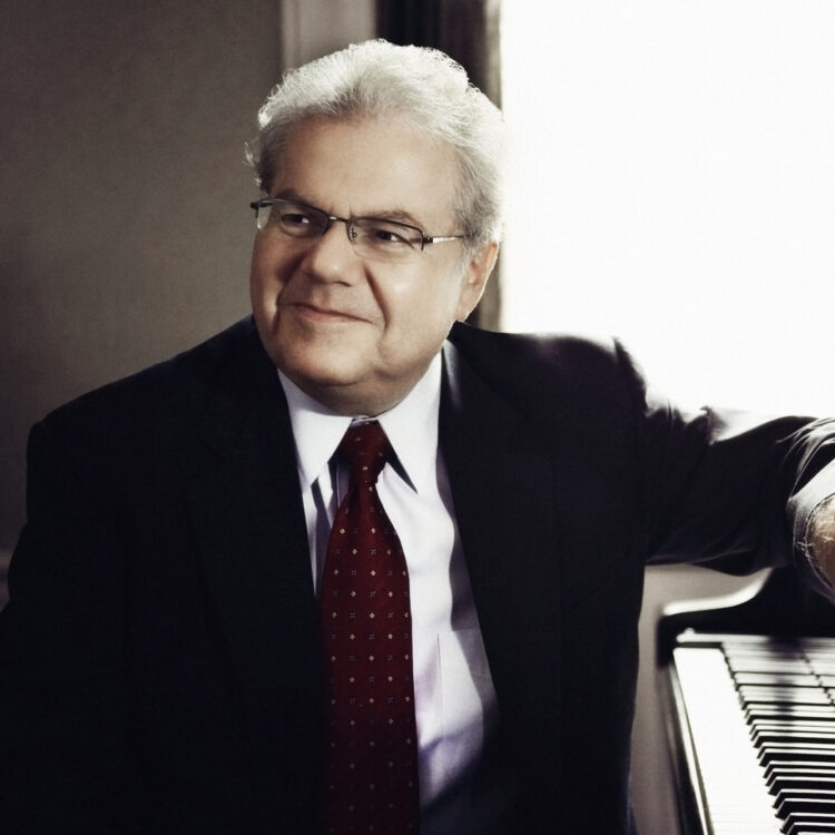 Emanuel Ax sitting a piano and smiling