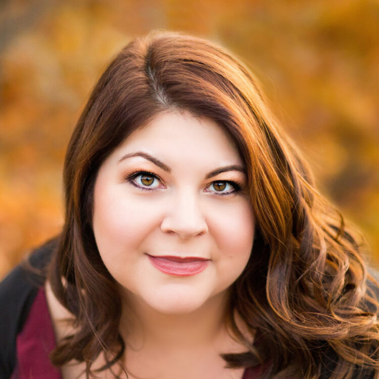 A headshot of Michelle Trainor with a background of fall colored leaves