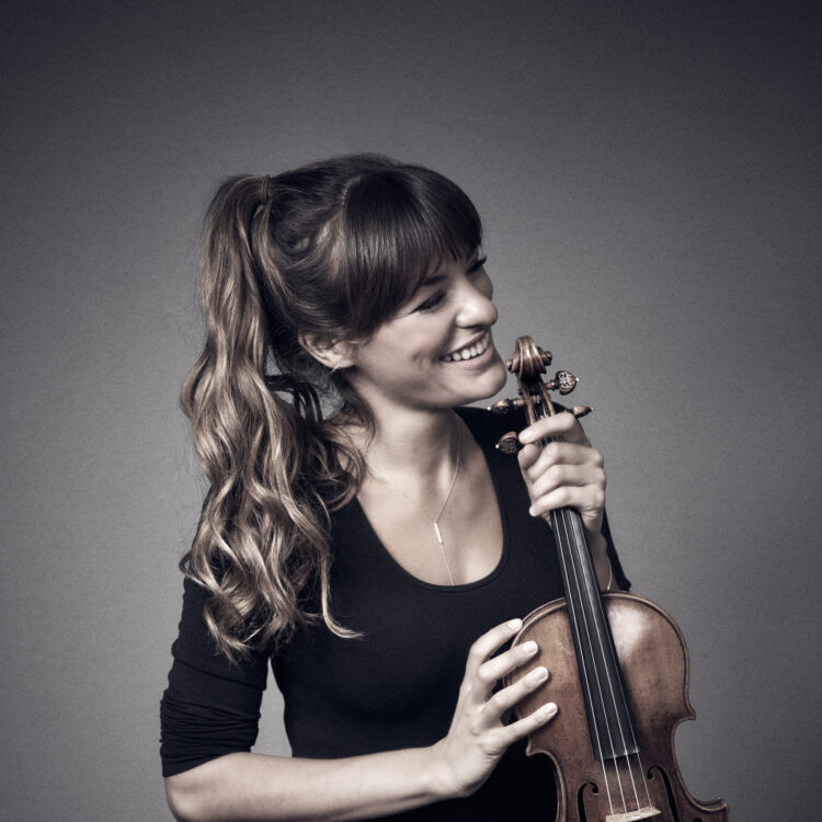 Nicola Benedetti smiling, looking to her right and holding her violin