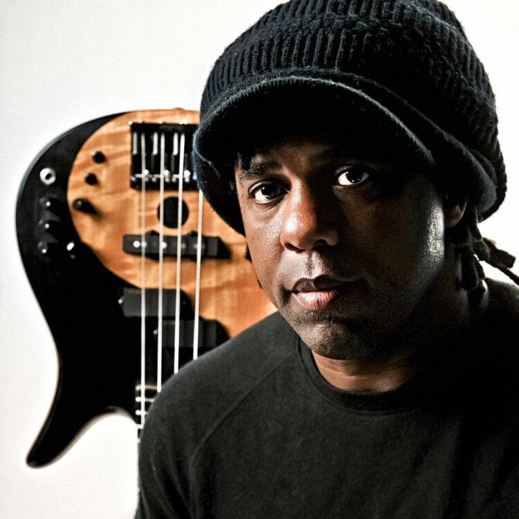 Victor Wooten sitting in front of an upside-down electric bass