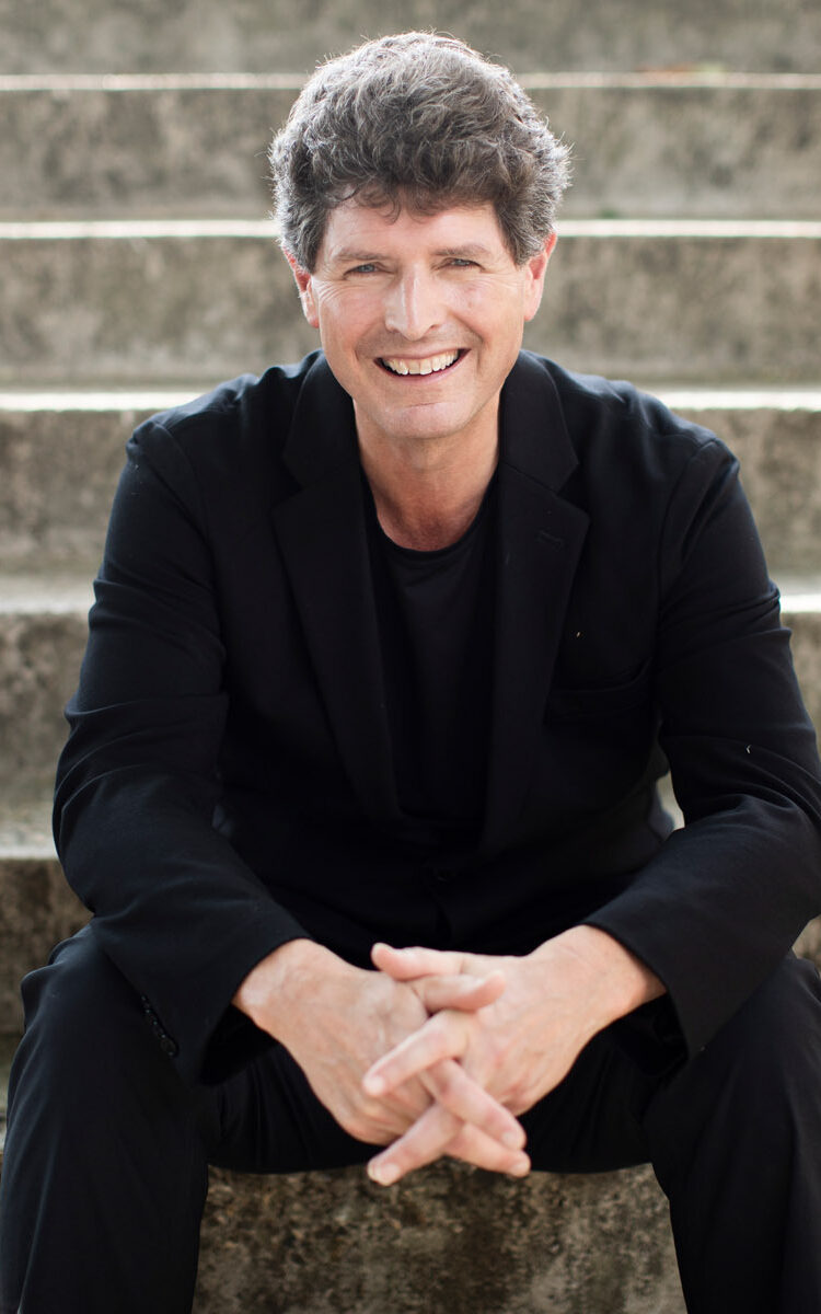 Clark Rundell sitting on stairs with a big smile
