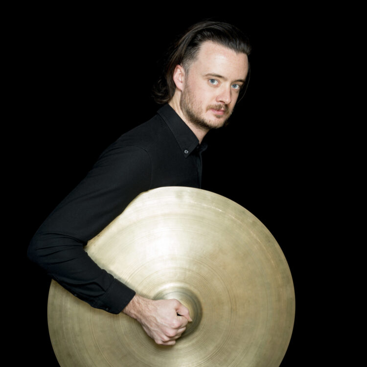 Kyle Brightwell headshot with large cymbal