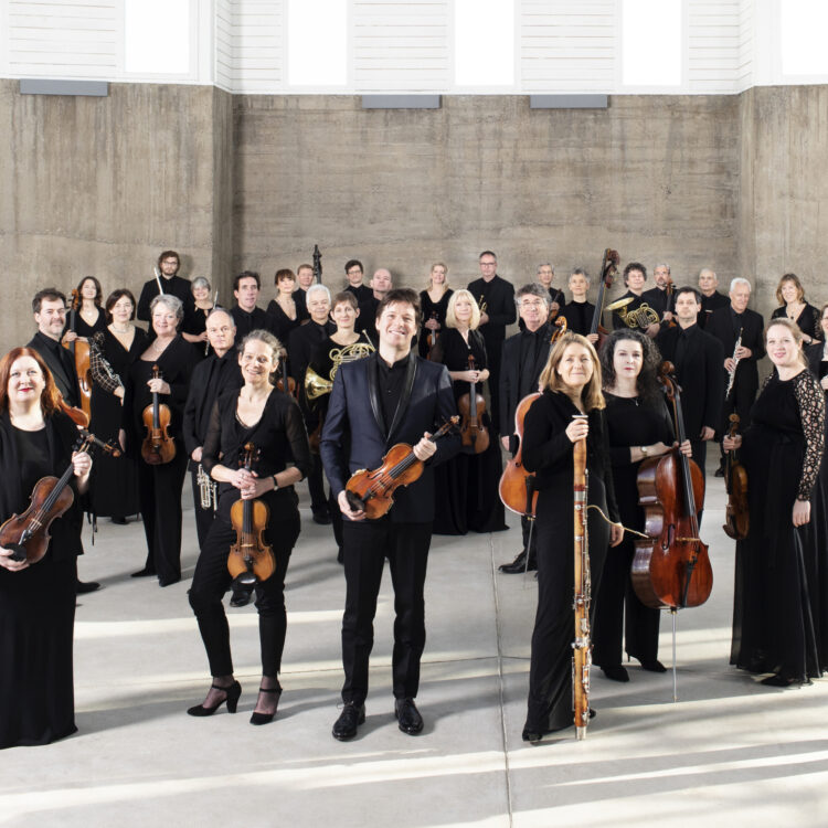 Academy of St Martin ensemble with Joshua Bell, standing in front of a beige background