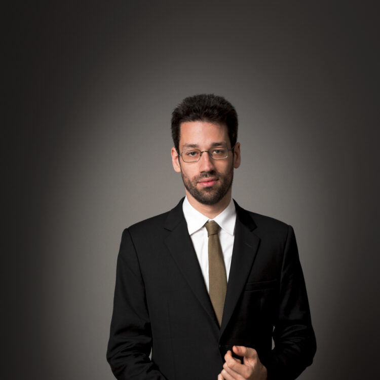 Jonathan Biss standing in front of a black background