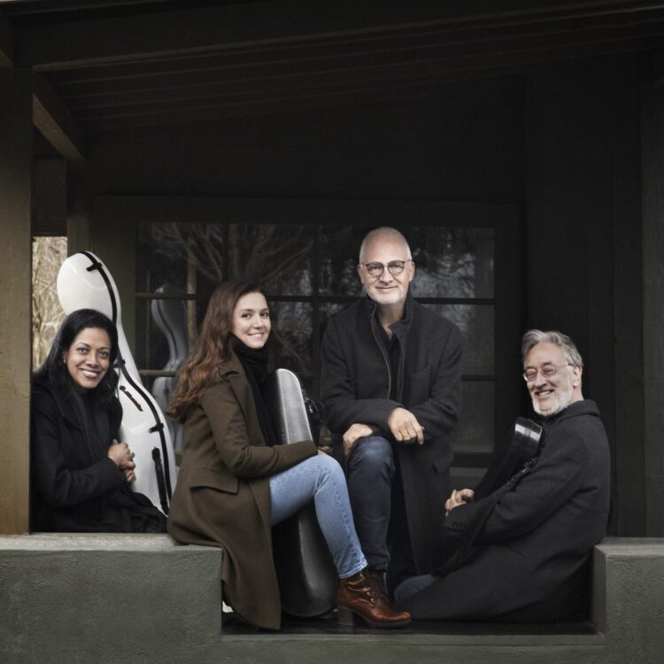 The four members of the Juilliard String Quartet posing for the camera with their instrument cases.