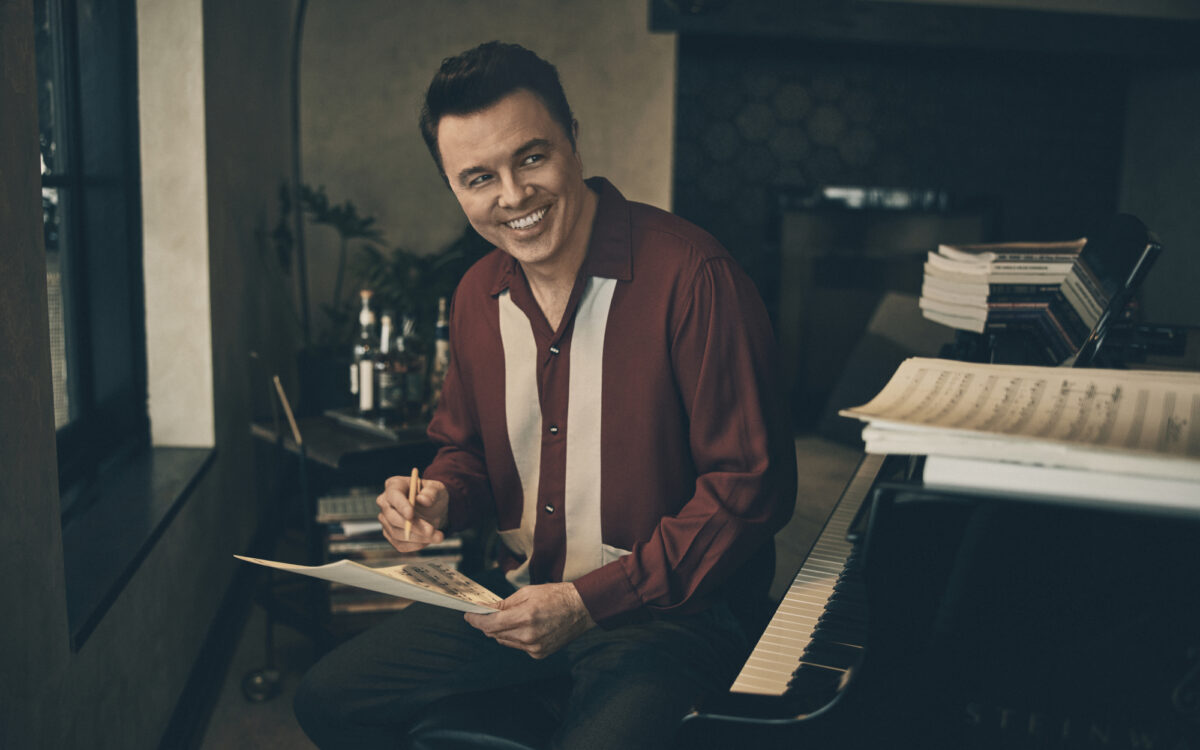Seth MacFarlane sitting at a piano writing music.