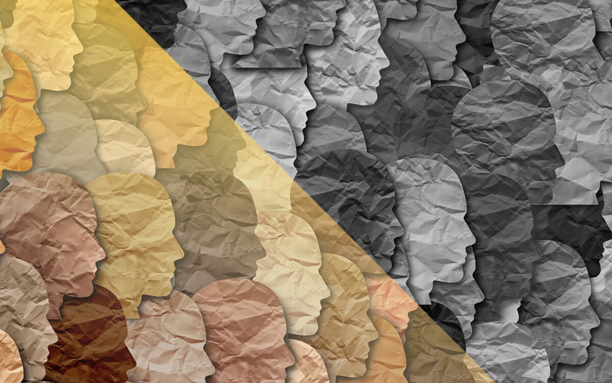 Different colored head profiles cut out of paper in a collage.