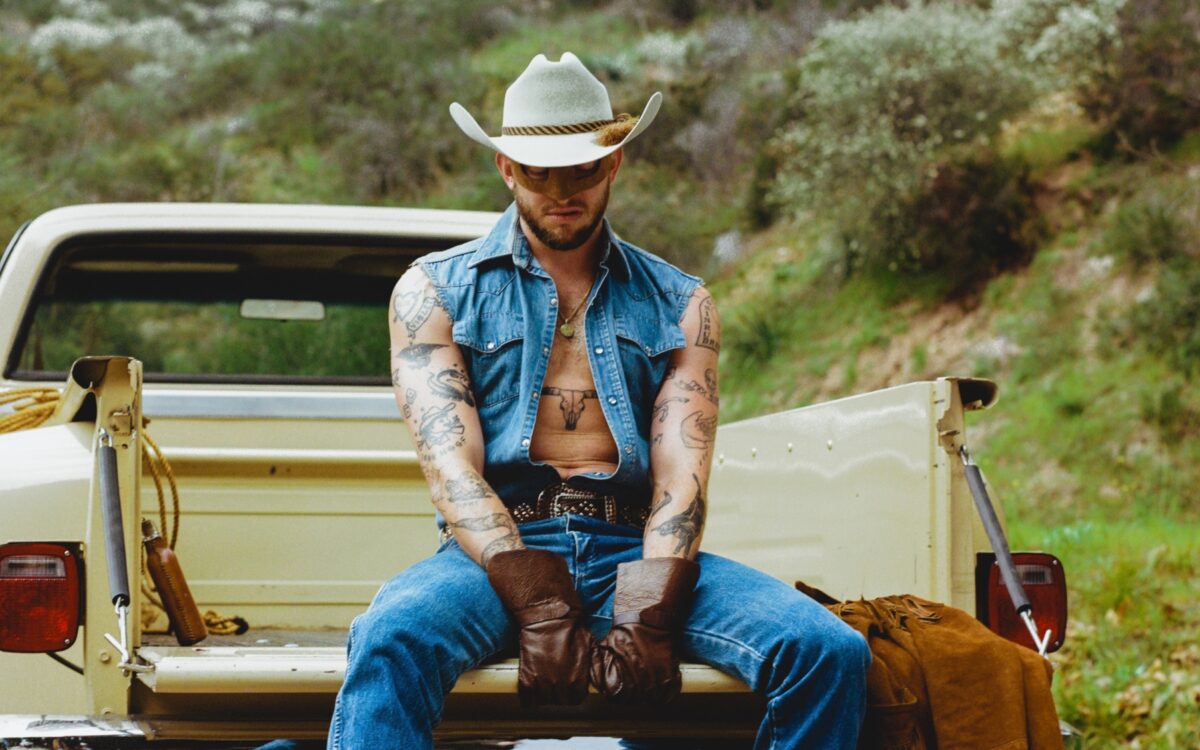 Orville Peck sitting in the bed of a pickup truck.