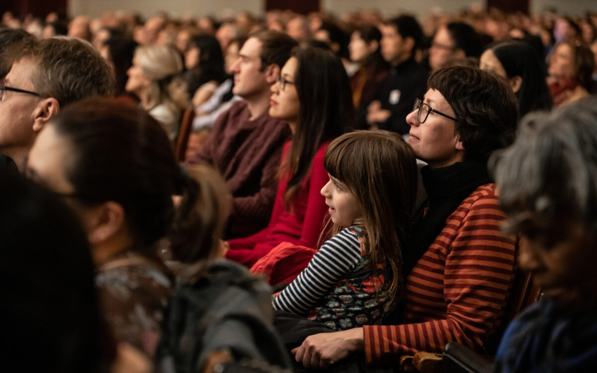 A young girl sit's on a woman's lap as they watch a BSO concert in Symphony Hall