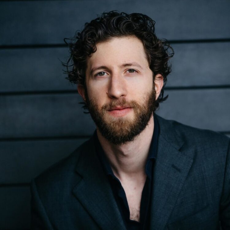 Headshot of David Leigh wearing a dark shirt and suit jacket.
