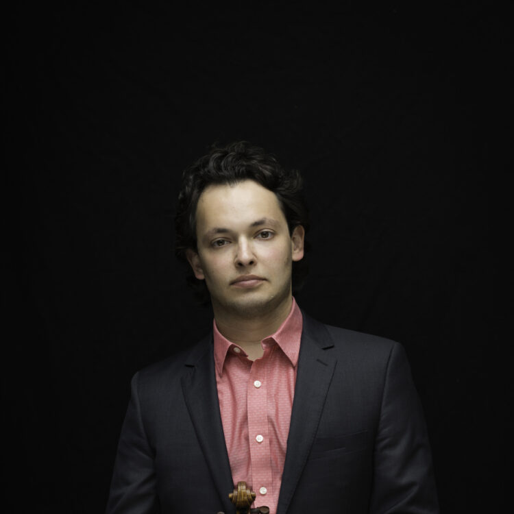 Yevgeny Kutik standing and holding his violin.