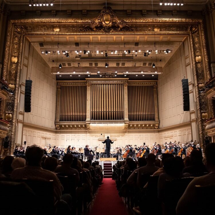 Looking down the center aisle of Symphony Hall with a full house and stage